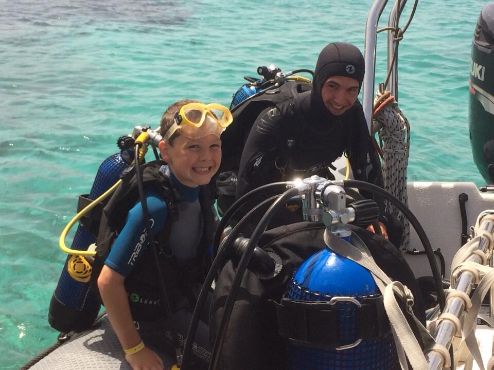 happy child diver and diving instructor on the boat